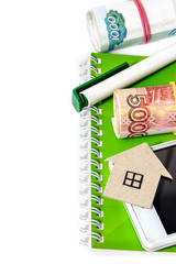 Paper house, Russian money, a pen and a notebook. Vertical edge
