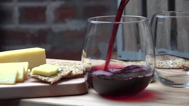 Pouring wine slow motion with crackers and cheese
