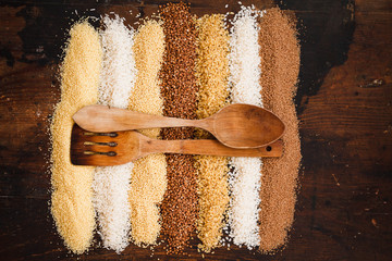 A variety of cereals separated into straight rows with aged wooden spoons. flat lay. 