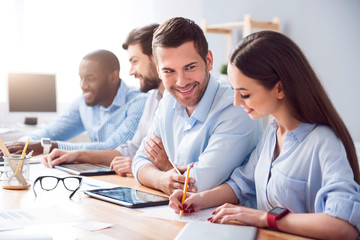 Cheerful smiling colleagues sitting at the table