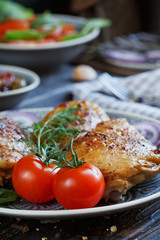 Roasted chicken and vegetables on dark wooden background