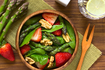Fresh strawberry, green asparagus, baby spinach and walnut salad served in wooden bowl,...