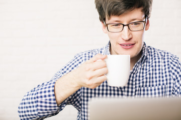 Man drinking coffee and using laptop