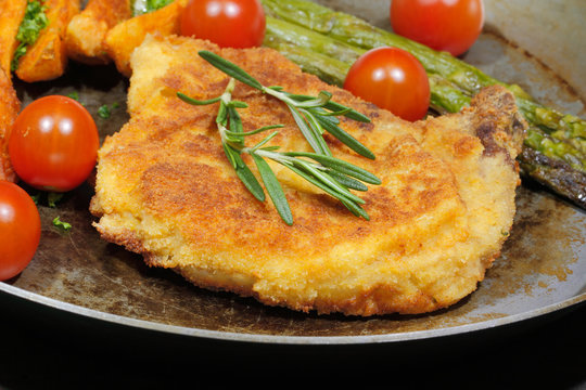 Cutlet with potato wedges, tomatoes, green asparagus, garnished