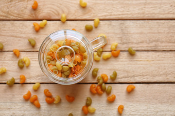 Colorful pasta in glass cup on wooden table