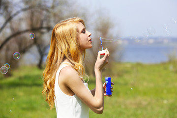 Young beautiful woman with bubbles on meadow