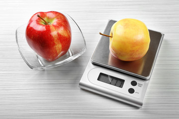 Apple with digital kitchen scales on wooden background