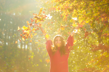 Woman playing with autumnal leaves.