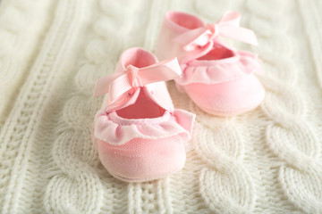 Fototapeta na wymiar Baby booties on knitted plaid, closeup