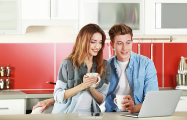 Obraz na płótnie Canvas Couple with laptop in kitchen