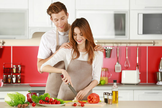 Couple in aprons cooking in kitchen
