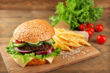 Big hamburger with fries on wooden background