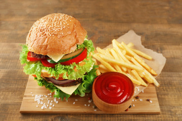 Double hamburger with fries on wooden background