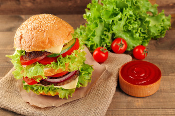 Big hamburger with ketchup on wooden background