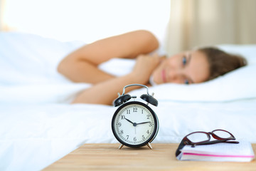 A young woman putting her alarm clock off in the morning