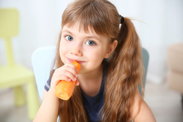 Little girl with carrot in the living room
