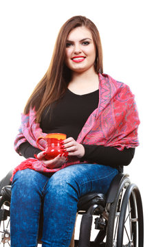Woman invalid girl on wheelchair holds tea mug