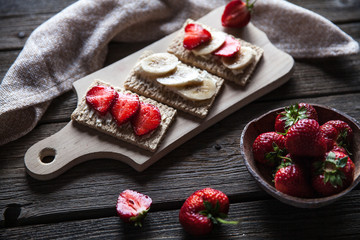 Fruity toast on wooden background. Strawberries, bread, butter and cheese.Vintage style