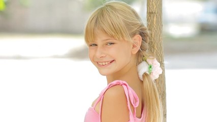 Happy kids, portrait of cute little girl turning and smiling at camera near tree outdoors