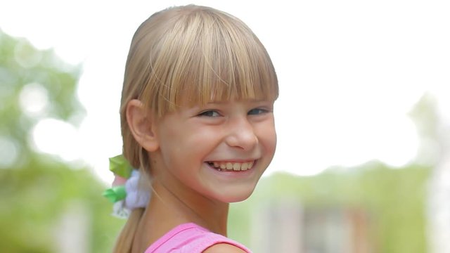 Happy kids, little girl turning and smiling at camera, children portrait outdoors