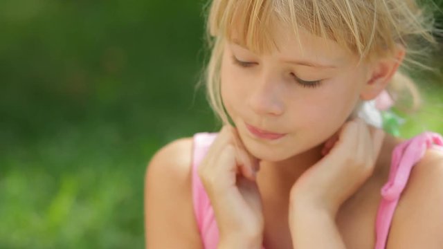 Sad face little girl, close up of pensive sulky or angry child sitting alone outdoors, kids emotion portrait