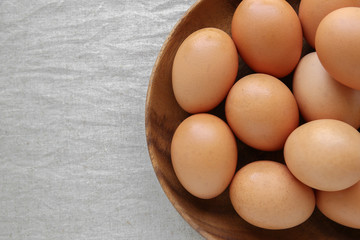 Eggs in wooden bowl on linen copy space background