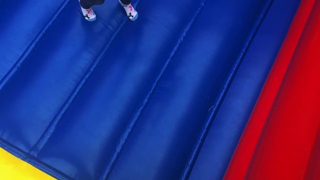 Above view of a young girl (age 6) jumps on bouncing castle. Children and childhood concept  copy space