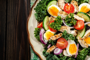 Fresh salad with chicken, tomatoes, eggs and lettuce on plate