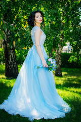 Bride. Beautiful young brunette woman in a Park with bouquet on a warm summer day.