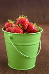 Strawberries with stems in a green bucket
