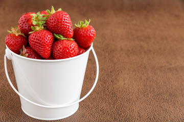 Strawberries with stems in a white bucket
