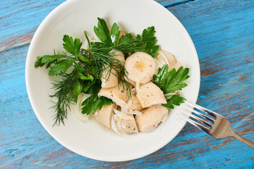 Salted milk mushrooms served in a white plate on a wooden table