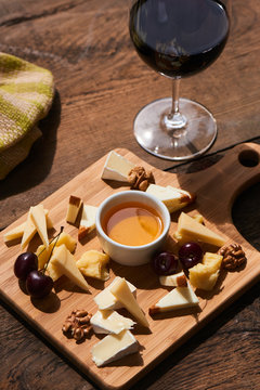 Healthy Breakfast from a set of cheese Parmesan, mozzarella, Camembert on a wooden Board and a glass of red wine