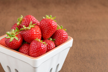 Strawberries with stems in a white container
