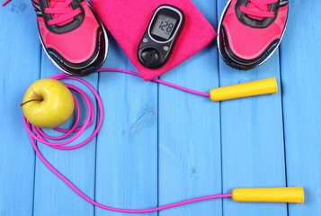 Glucometer, sport shoes, fresh apple and accessories for fitness on blue boards, copy space for text