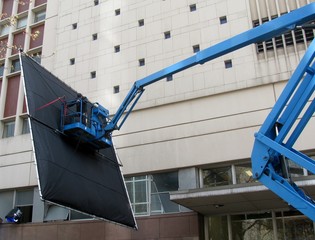 Film Lighting Technician at work - huge reflector on a crane / jib