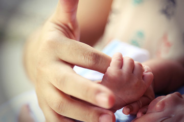 Hand of a baby holding mother's finger