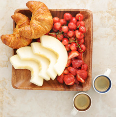 Breakfast with coffee, croissants and fruit - melon, strawberrie