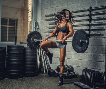 Female with barbell in a gym club.