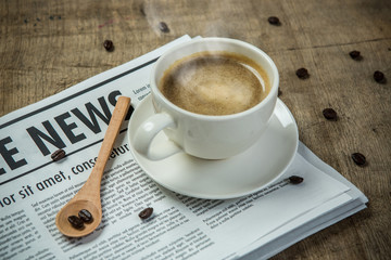 A newspaper and a cup of coffee on a wooden table