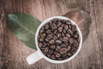 Coffee beans in cup on wooden