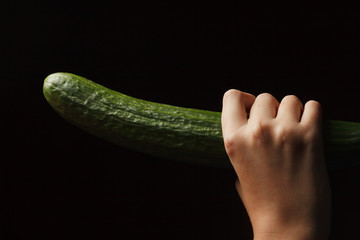 Beautiful red head girl licking ripe cucmber on the vine sexually with her seductive tongue; foreplay with food and feeding on black background. very similar blowjob
