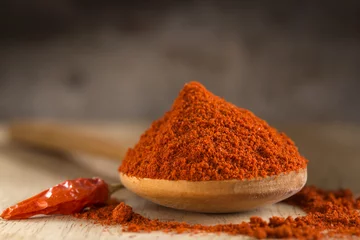 Zelfklevend Fotobehang Spoon filled with red hot paprika powder © Sebastian Studio