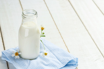 A bottle of milk on a white wooden table on a blue background, t