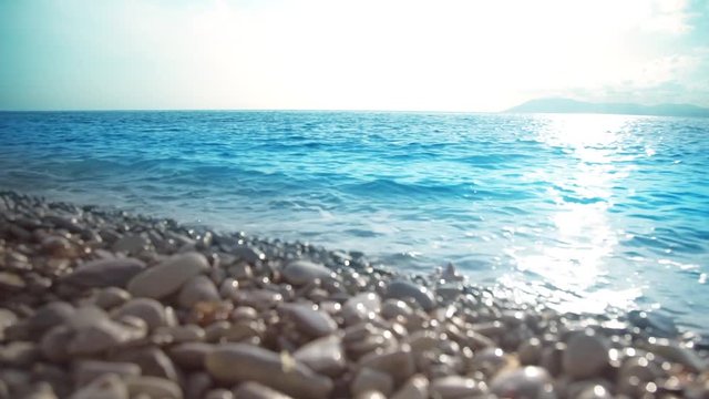Sea, peeble shore and waves. Seascape at sunset in slow motion.
