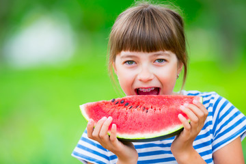 Child eating watermelon. Kids eat fruits in the garden. Pre teen girl in the garden holding a slice of water melon. happy girl kid eating watermelon. Girl kid with gasses and teeth braces.