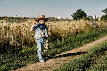 Naklejka na ściany i meble Little boy dressed in Western style in the field , retro style