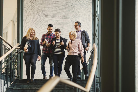 Team of creative business people walking downstairs at office