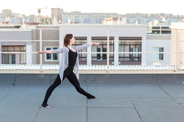 Fototapeta na wymiar Young woman doing yoga on the roof