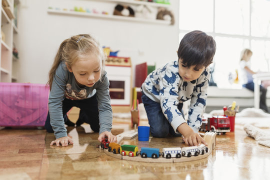 Kids playing with wooden train on floor 